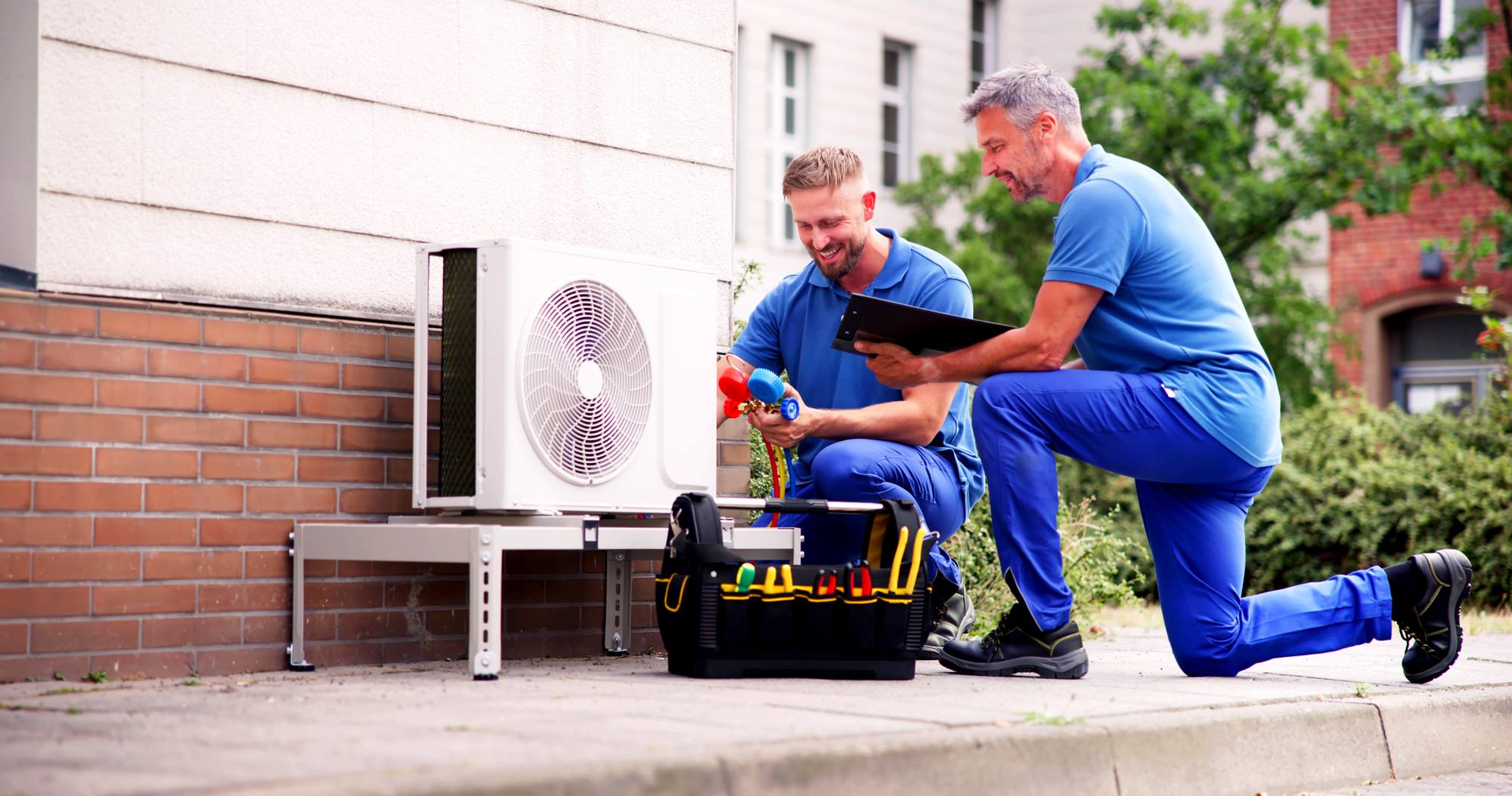 HVAC technicians reviewing an installation checklist beside a condenser unit